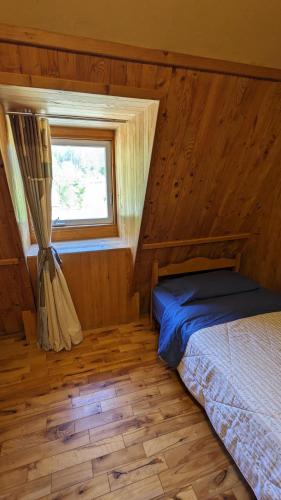 a bedroom with a bed in a room with a window at Grangette Entre Chiens et Loups in LʼAnse-Saint-Jean