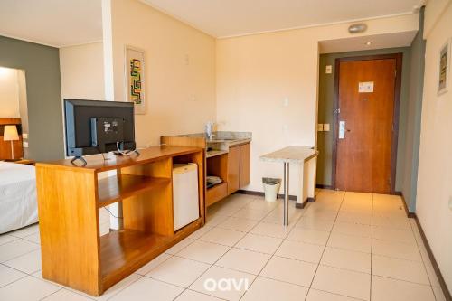 a room with a desk with a television and a bed at Interatlântico by Qavi in Natal