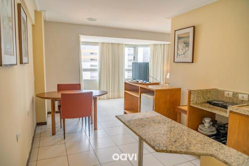 a living room with a table and a kitchen with a dining room at Interatlântico by Qavi in Natal