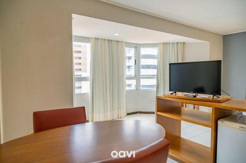 a living room with a table and a flat screen tv at Interatlântico by Qavi in Natal