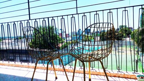 two chairs sitting in front of a fence at Apartamento Céntrico con Balcón in Paysandú