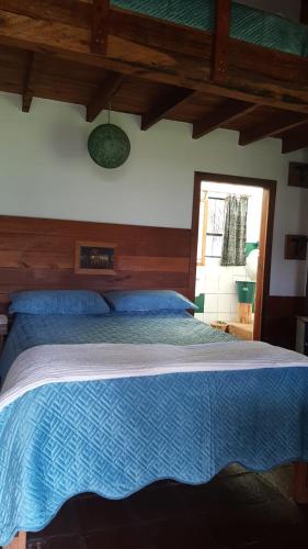 a bedroom with a bed with a blue comforter and a window at The Black Sheep Inn in Chugchilán