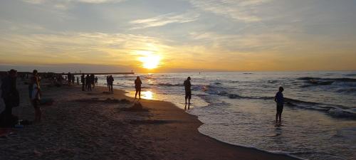a group of people standing on the beach at sunset at Apartament Pogodny in Łeba