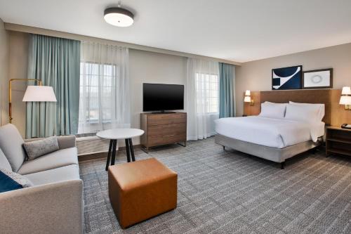 a hotel room with a bed and a tv at Staybridge Suites Bismarck by IHG in Bismarck
