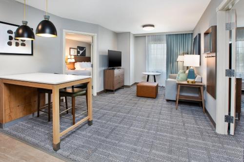 a hotel room with a desk and a bedroom at Staybridge Suites Bismarck by IHG in Bismarck