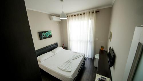 a bedroom with a white bed and a window at Kadrisa Hotel in Durrës