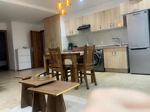 a kitchen with a table and chairs and a refrigerator at Appartement vu sur piscine à 5 minutes de la plage in Mansouria