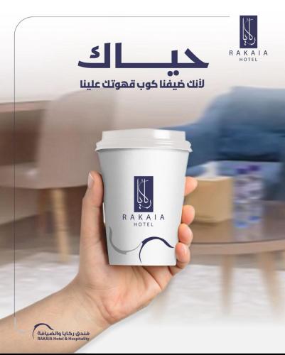 a hand holding a paper coffee cup in a store at ركايا الوسطى للشقق المخدومة in Hail