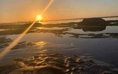 a body of water with the sun setting in the background at Appartement vu sur piscine à 5 minutes de la plage in Mansouria