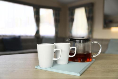 two white coffee mugs sitting on a coaster next to a juicer at The Crew's Nest in Port Seton