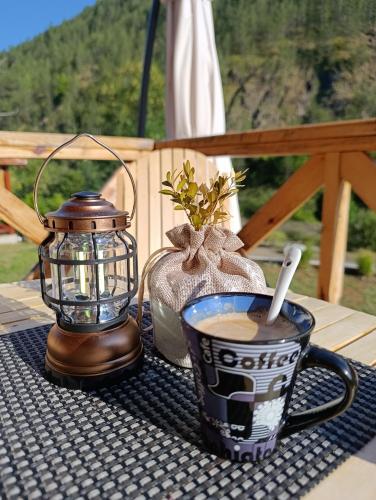 a cup of coffee and a lantern on a table at Dedin Konak in Mokra Gora