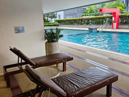 een zwembad met twee stoelen en een bank ernaast bij Kuma House Asoke in Bang Kapi