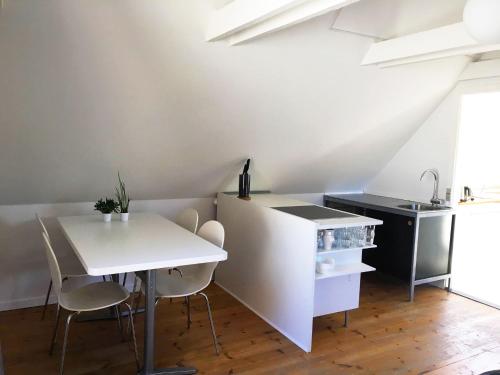 a kitchen with a white table and chairs and a sink at Ebogaard in Hillerød