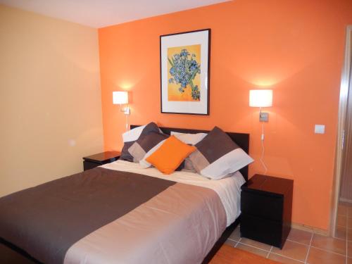 ein Schlafzimmer mit einem Bett mit orangefarbenen Wänden und 2 Lampen in der Unterkunft Apartamento Bela Vista in Porto Santo