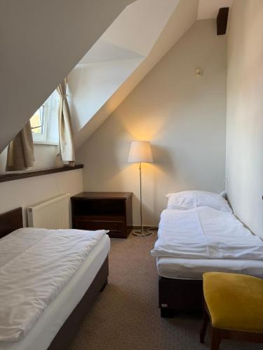 a bedroom with two beds and a table and a lamp at Bechnerův statek in Lány