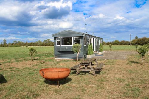 a tiny house and a picnic table in a field at Sheepy Lodge by SkyBears Holidays - Puppy Lounge, Arcades, Games room in Faldingworth