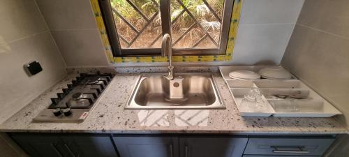 Una encimera de cocina con un fregadero y una estufa. en Les cocons du cap santa-clara à Libreville-Gabon, en Lope