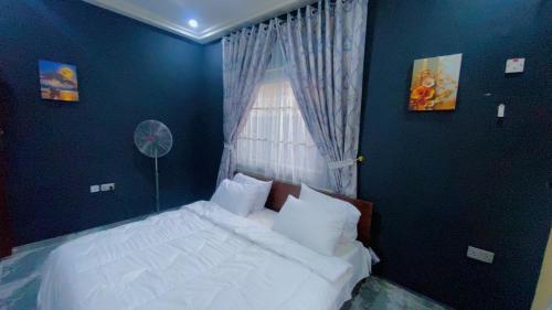 a bedroom with a white bed with a window at Rapid Roost Apartments in Umuahia