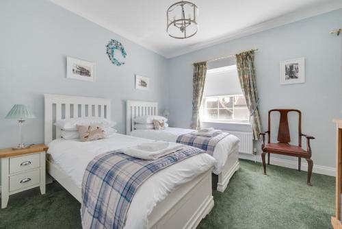 a bedroom with two beds and a chair at Pound Cottage in Holt