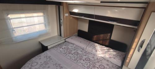 een kleine slaapkamer met een bed in een camper bij Autocaravana El quijote in Albacete