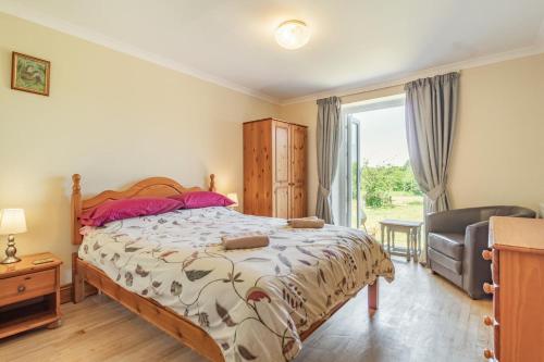 a bedroom with a bed and a chair and a window at Fieldview in East Barsham
