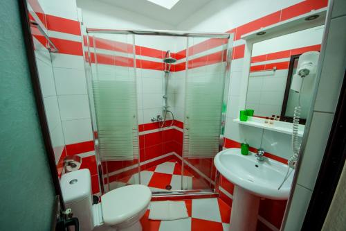 a red and white bathroom with a toilet and sink at Kadrisa Hotel in Durrës
