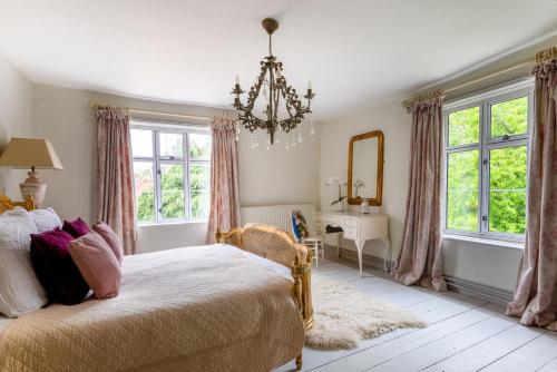 a bedroom with a bed and a mirror and windows at Church Farm in Halesworth