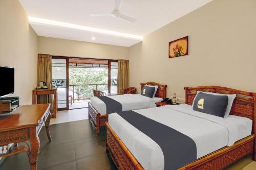 two beds in a room with a desk and a computer at OAK Edassery's Sealine Villa Stay in Cochin