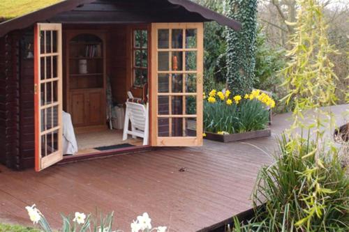 a wooden deck with a small shed with doors at The Stables in Ufford