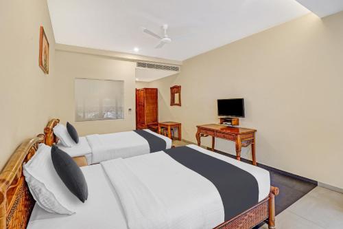 a hotel room with two beds and a desk at OAK Edassery's Sealine Villa Stay in Cochin