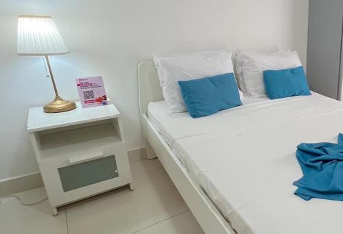 Una cama blanca con almohadas azules y una lámpara en una mesa. en Good location Good price, en Punta Cana