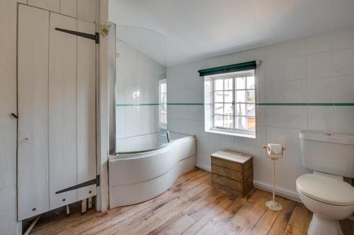 a bathroom with a tub and a toilet and a sink at Jasmine Cottage in Woodbridge