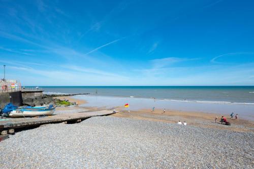 a beach with a pier with a boat on it at The Anchorage in Sheringham