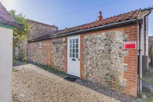a brick building with a white door and a wall at The Anchorage in Sheringham