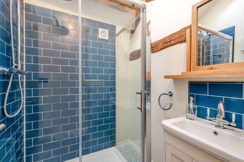 a bathroom with a blue tiled shower and a sink at The Coach House at Hill House in Eye