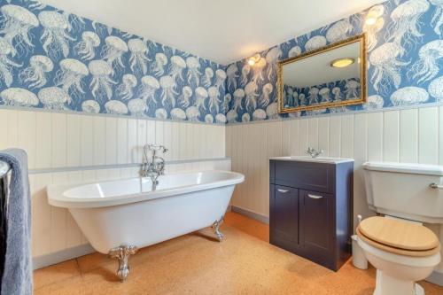 a bathroom with a tub and a toilet and a sink at Three Ash Farm in Bungay