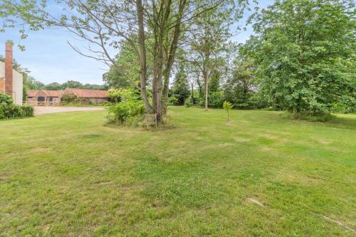 a field with a tree and a house at Three Ash Farm in Bungay