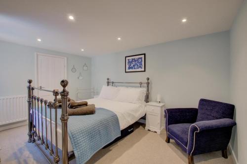 ein Schlafzimmer mit einem Bett und einem blauen Stuhl in der Unterkunft James Cottage in Southwold