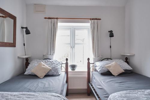 zwei Einzelbetten in einem Schlafzimmer mit Fenster in der Unterkunft Kingfisher Cottage in Youlgreave