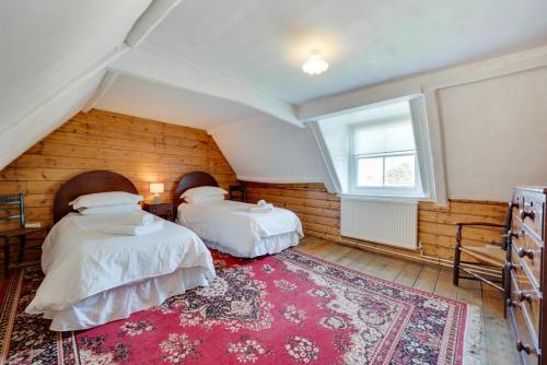 a attic room with two beds and a red rug at Old Brewery House in Orford