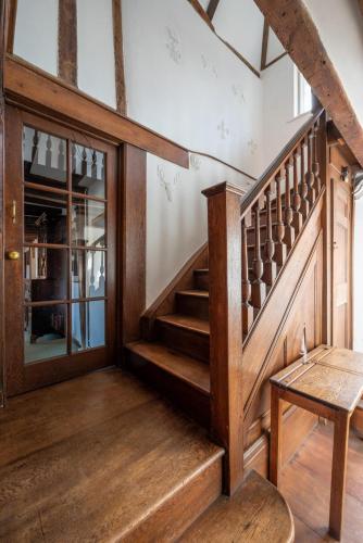 a room with a wooden staircase and a table at Old Brewery House in Orford