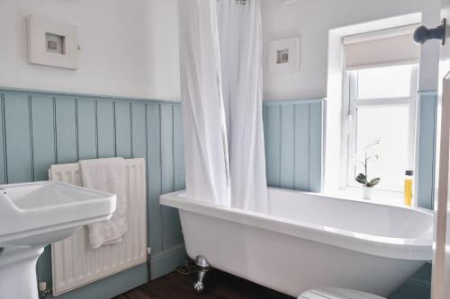 ein Badezimmer mit Badewanne und Waschbecken und einem Fenster in der Unterkunft Kingfisher Cottage in Youlgreave