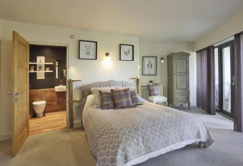 a bedroom with a large bed and a bathroom at Stone Farm in Lavenham