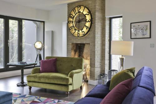 a living room with a couch and a clock on the wall at Stone Farm in Lavenham