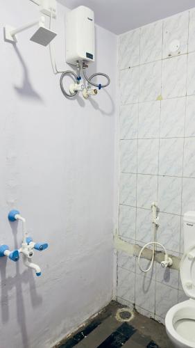 a bathroom with a toilet and a white tiled wall at StayIn-SGH in Mysore