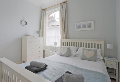 a bedroom with a white bed with two pillows at Stones Throw in Southwold