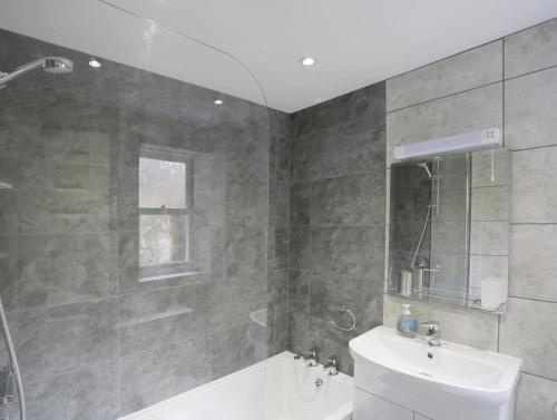 a bathroom with a shower and a tub and a sink at Stones Throw in Southwold