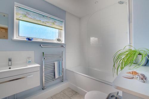 a bathroom with a tub and a sink and a window at Seaglass Cottage in Hythe