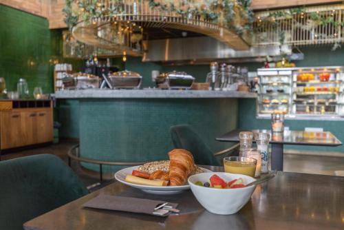 a table with a plate of bread and a bowl of fruit at Leonardo Hotel Vinkeveen Amsterdam in Vinkeveen