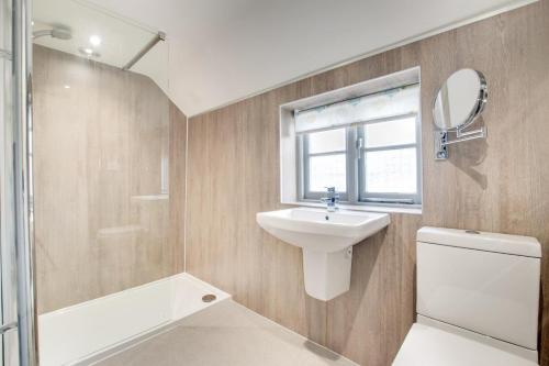 een badkamer met een wastafel, een toilet en een spiegel bij Box Cottage in Snape